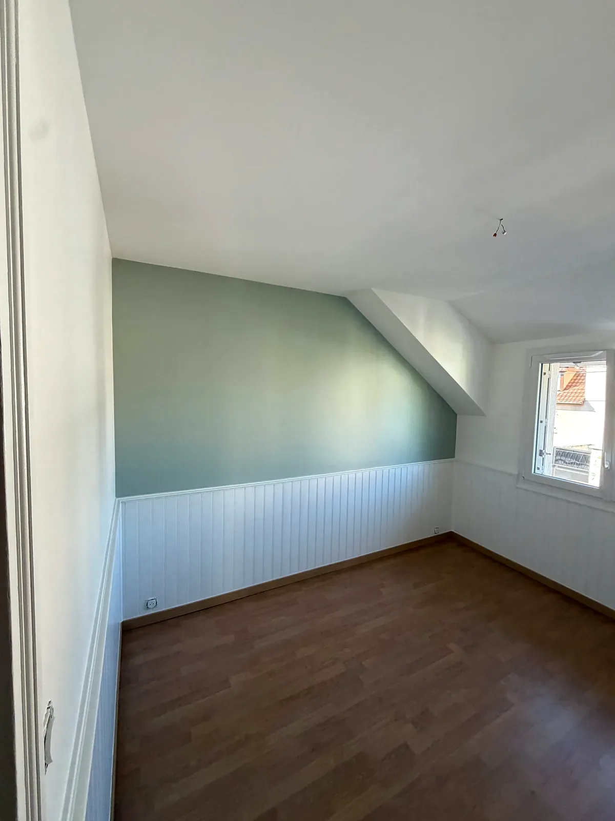Pièce sous combles rénovée avec soubassement blanc et mur vert sauge