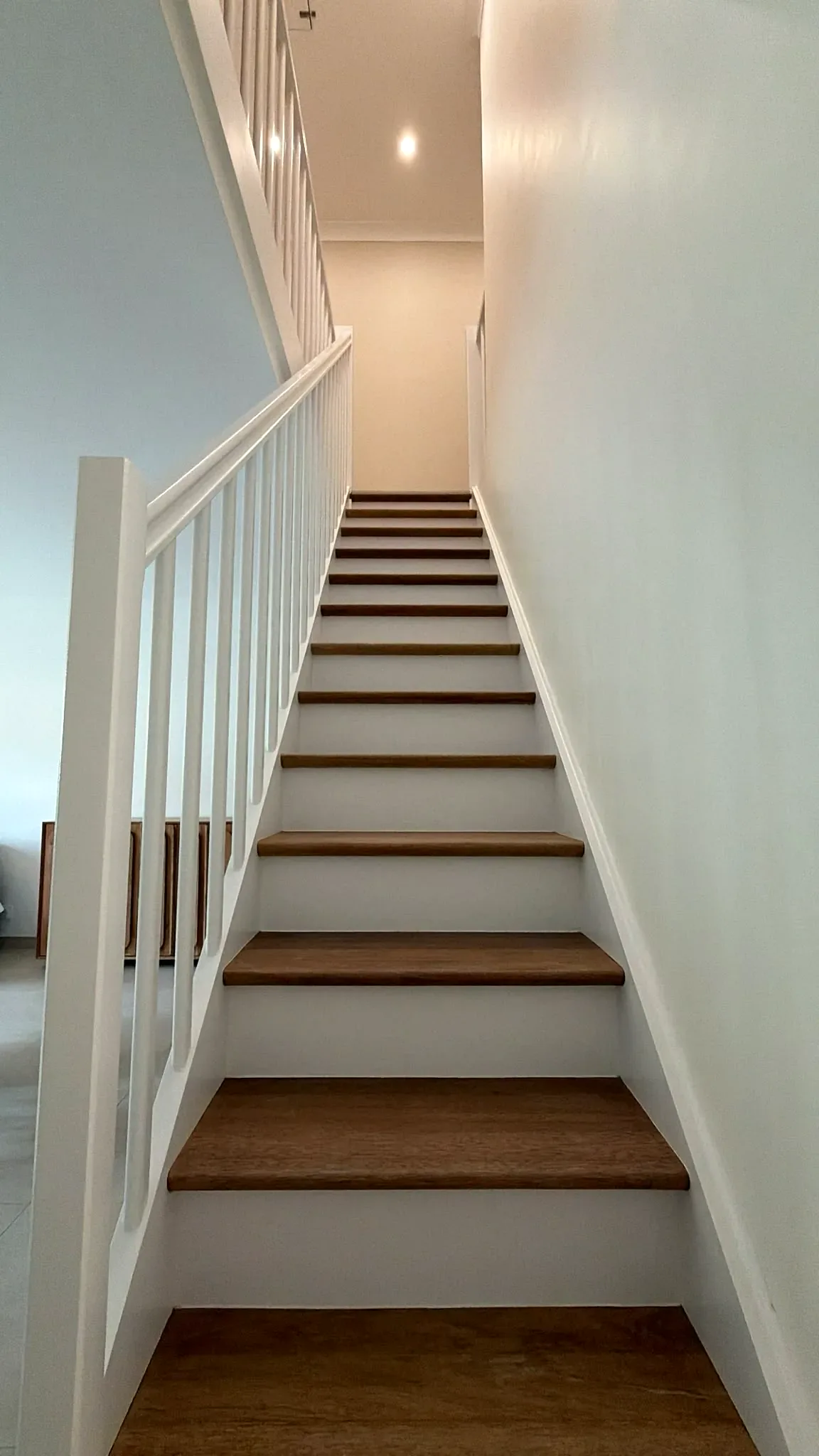 Escalier rénové avec contremarches et garde-corps blancs, marches en bois