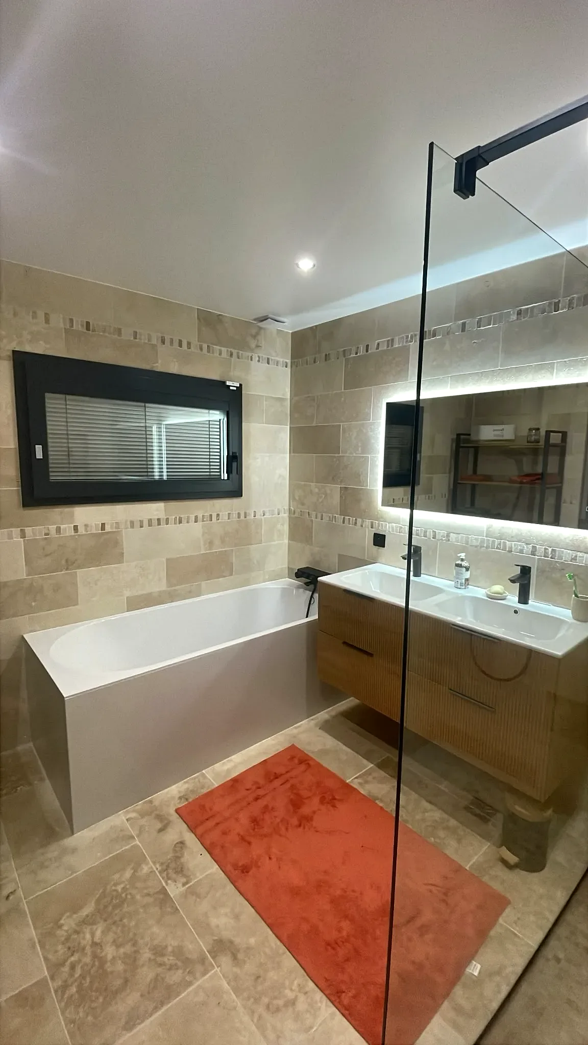 Salle de bain rénovée avec baignoire, douche vitrée et meuble double vasque