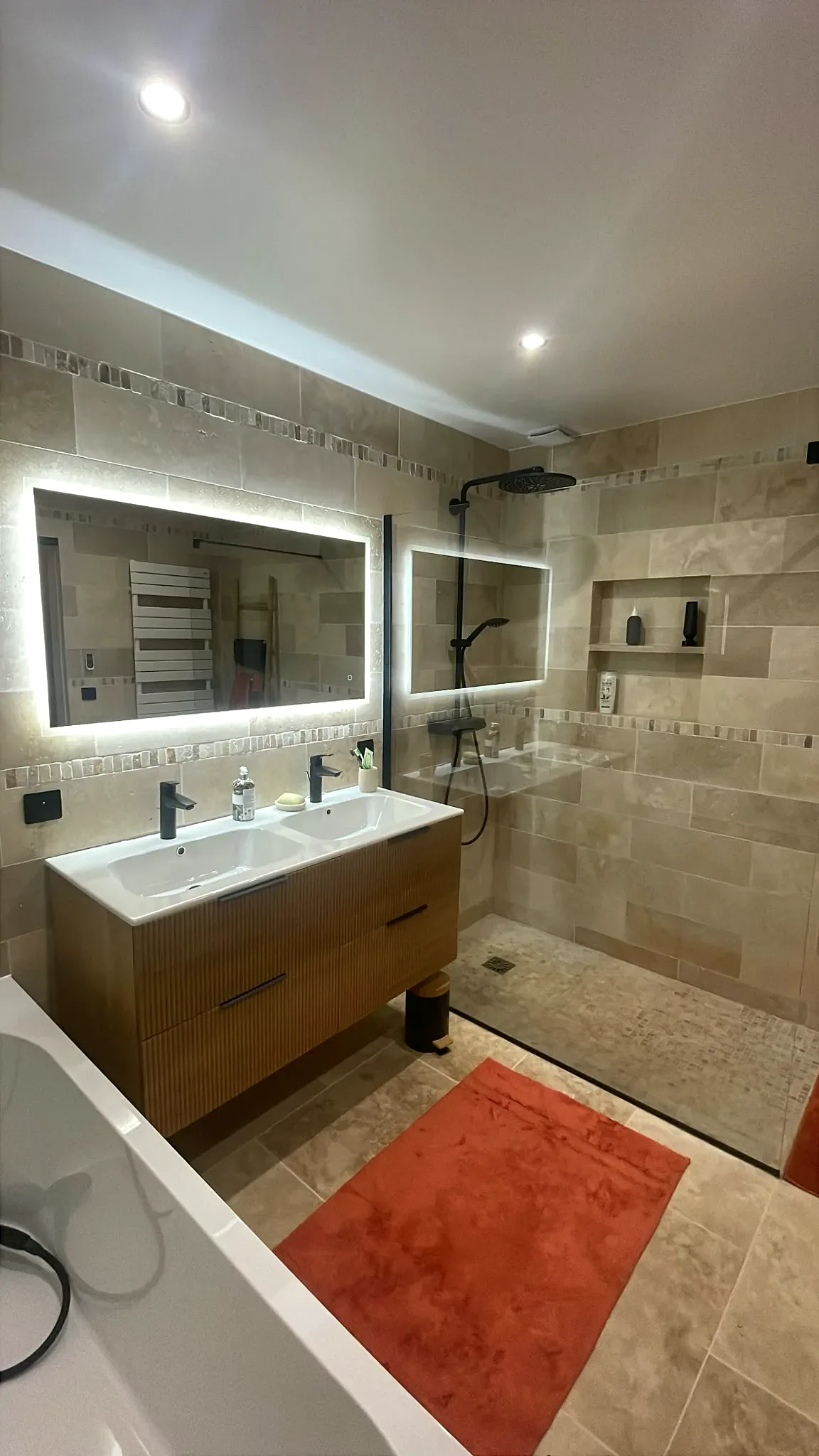 Salle de bain rénovée avec miroir lumineux et robinetterie noire